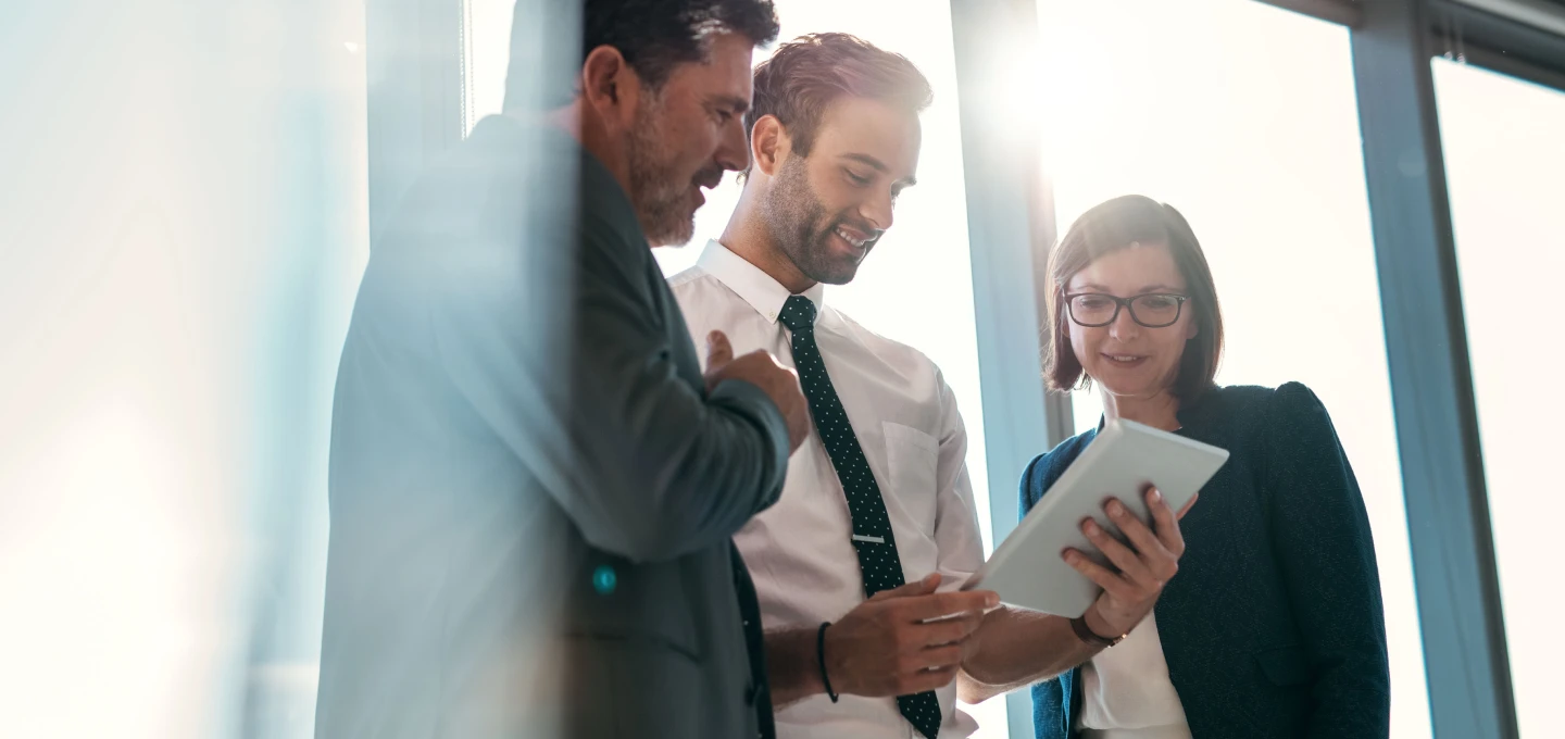 Three people working and looking at a notebook