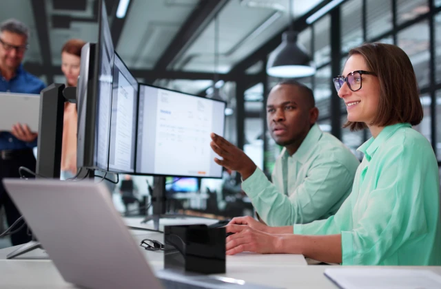 People working on a desk looking at a screen
